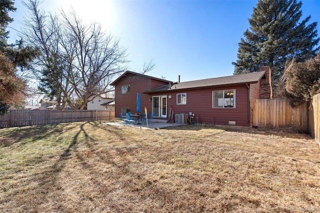 rear view of house featuring a lawn, a patio, a fenced backyard, a chimney, and central air condition unit