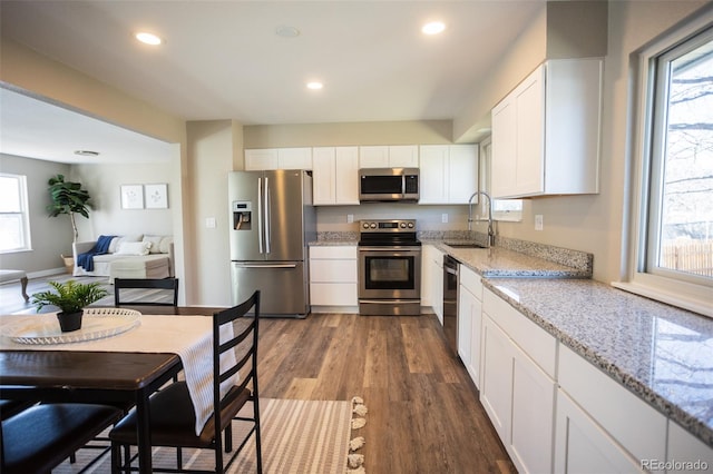 kitchen featuring sink, white cabinetry, light stone counters, dark hardwood / wood-style floors, and stainless steel appliances