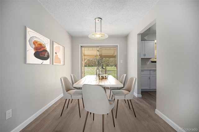 8346 W Woodard Dr, Lakewood, CO 80227 - dining area with wood finished floors, baseboards, and a textured ceiling