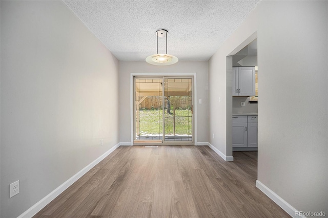 8346 W Woodard Dr, Lakewood, CO 80227 - unfurnished dining area with wood finished floors, a textured ceiling, and baseboards