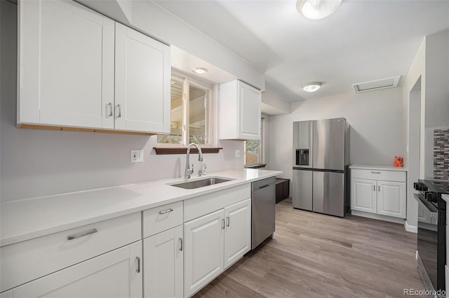 8346 W Woodard Dr, Lakewood, CO 80227 - kitchen with stainless steel appliances, a sink, white cabinetry, and light countertops