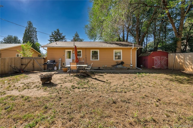 rear view of property featuring a fire pit, a storage shed, a lawn, and a patio