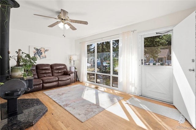 living room featuring ceiling fan, a wood stove, and hardwood / wood-style flooring