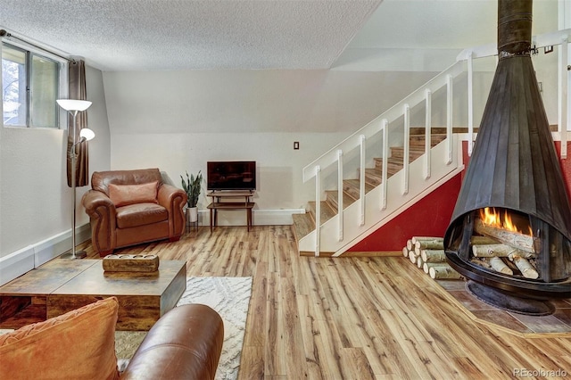 living room featuring a wood stove, a textured ceiling, and light hardwood / wood-style flooring