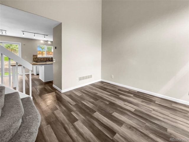 interior space with rail lighting and dark hardwood / wood-style flooring