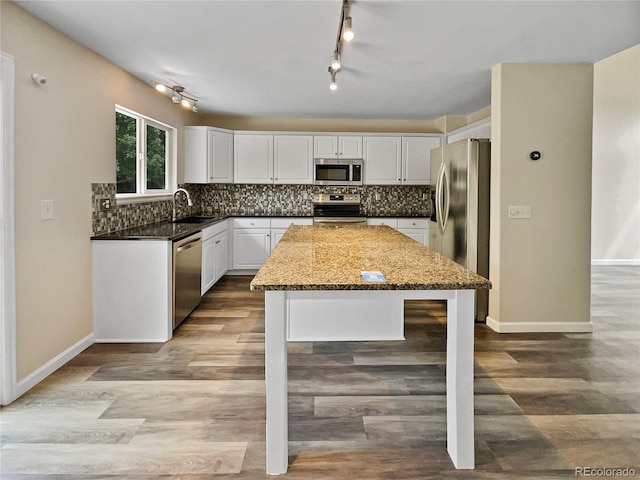 kitchen featuring sink, white cabinetry, stainless steel appliances, tasteful backsplash, and dark stone counters