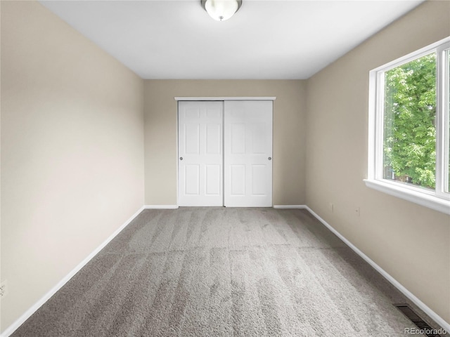 unfurnished bedroom with a closet, carpet floors, and multiple windows