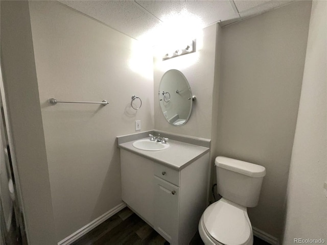 bathroom featuring vanity, wood-type flooring, a drop ceiling, and toilet