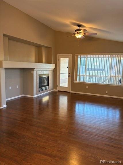 unfurnished living room featuring baseboards, a ceiling fan, dark wood-type flooring, vaulted ceiling, and a fireplace