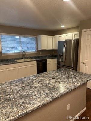 kitchen featuring white cabinets, dark stone counters, dishwasher, stainless steel fridge with ice dispenser, and a sink