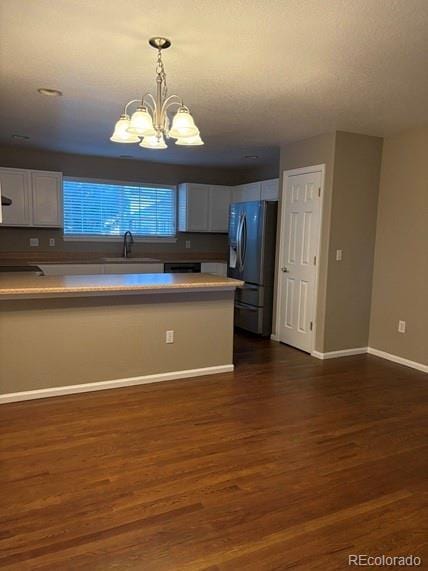 kitchen with dark wood-style floors, decorative light fixtures, stainless steel refrigerator with ice dispenser, white cabinets, and a sink