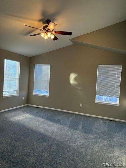 spare room with lofted ceiling, dark colored carpet, a ceiling fan, and baseboards