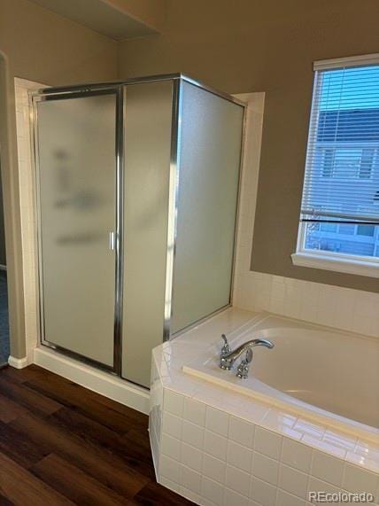 bathroom featuring a stall shower, a garden tub, and wood finished floors