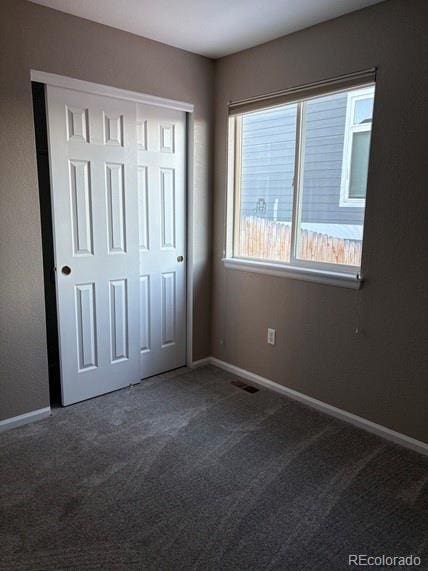 unfurnished bedroom with baseboards, a closet, visible vents, and carpet flooring