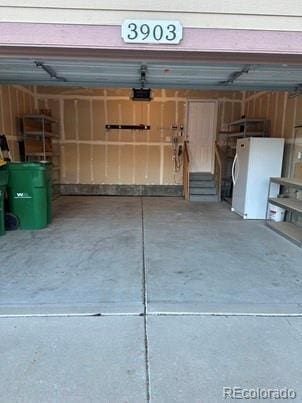 garage featuring a garage door opener and freestanding refrigerator