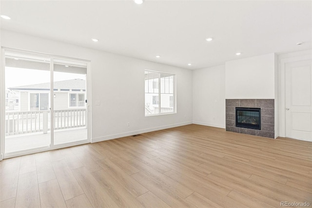20665 E 57th Dr, Aurora, CO 80019 - unfurnished living room with light wood-style flooring, baseboards, recessed lighting, and a tile fireplace