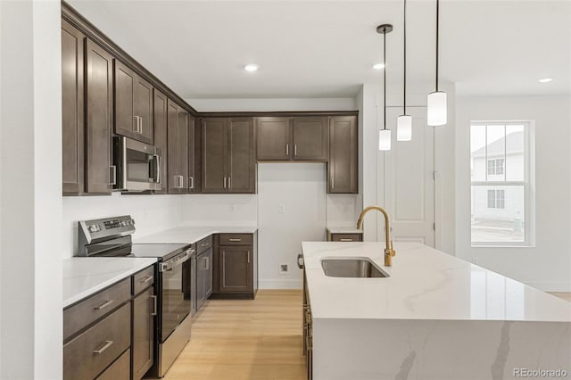 20665 E 57th Dr, Aurora, CO 80019 - kitchen featuring stainless steel appliances, a sink, dark brown cabinets, light wood finished floors, and hanging light fixtures