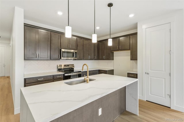 20665 E 57th Dr, Aurora, CO 80019 - kitchen with appliances with stainless steel finishes, a sink, dark brown cabinetry, light wood finished floors, and light stone countertops