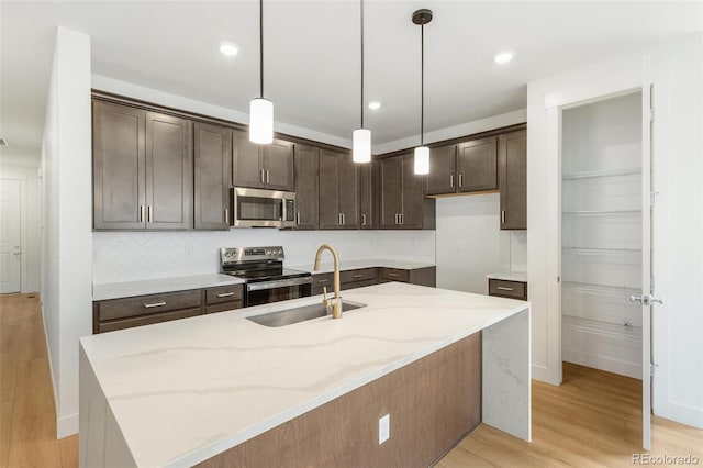 20665 E 57th Dr, Aurora, CO 80019 - kitchen featuring appliances with stainless steel finishes, a sink, dark brown cabinets, light stone countertops, and light wood-type flooring