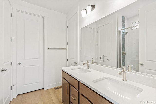 20665 E 57th Dr, Aurora, CO 80019 - bathroom featuring wood finished floors, tiled shower, and double vanity