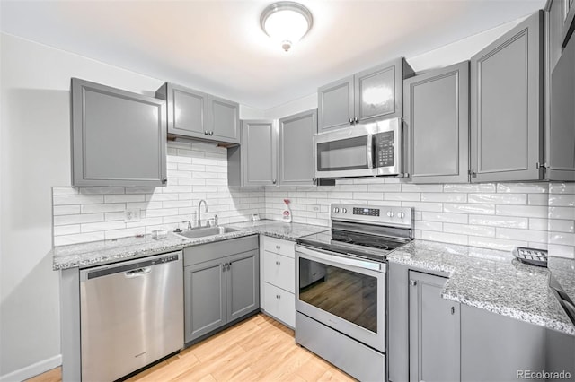 kitchen featuring light hardwood / wood-style flooring, stainless steel appliances, backsplash, sink, and gray cabinets