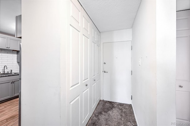 hallway featuring a textured ceiling, sink, and light wood-type flooring