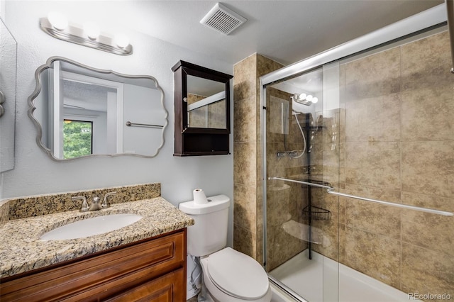 bathroom featuring visible vents, a shower stall, toilet, and vanity