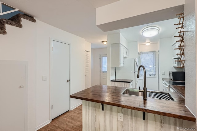 kitchen featuring white cabinets, stainless steel appliances, light wood-type flooring, wood counters, and sink