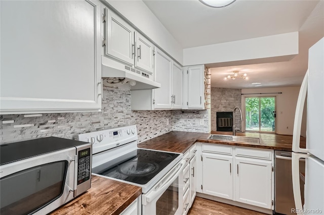 kitchen featuring light hardwood / wood-style floors, tasteful backsplash, white cabinetry, an inviting chandelier, and appliances with stainless steel finishes