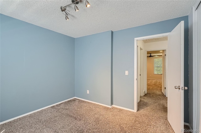 carpeted spare room featuring a textured ceiling and track lighting