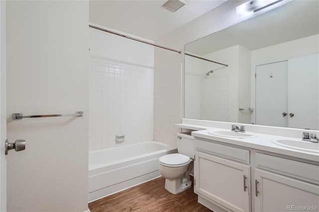 full bathroom with tiled shower / bath combo, vanity, toilet, and hardwood / wood-style flooring