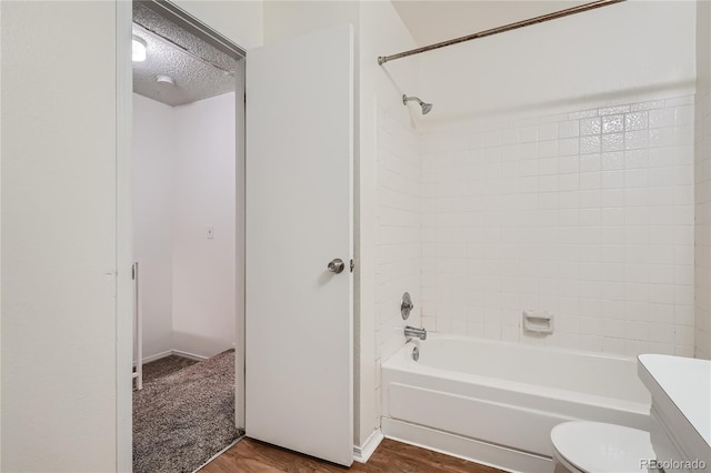 full bathroom with vanity, a textured ceiling, hardwood / wood-style floors, toilet, and tiled shower / bath