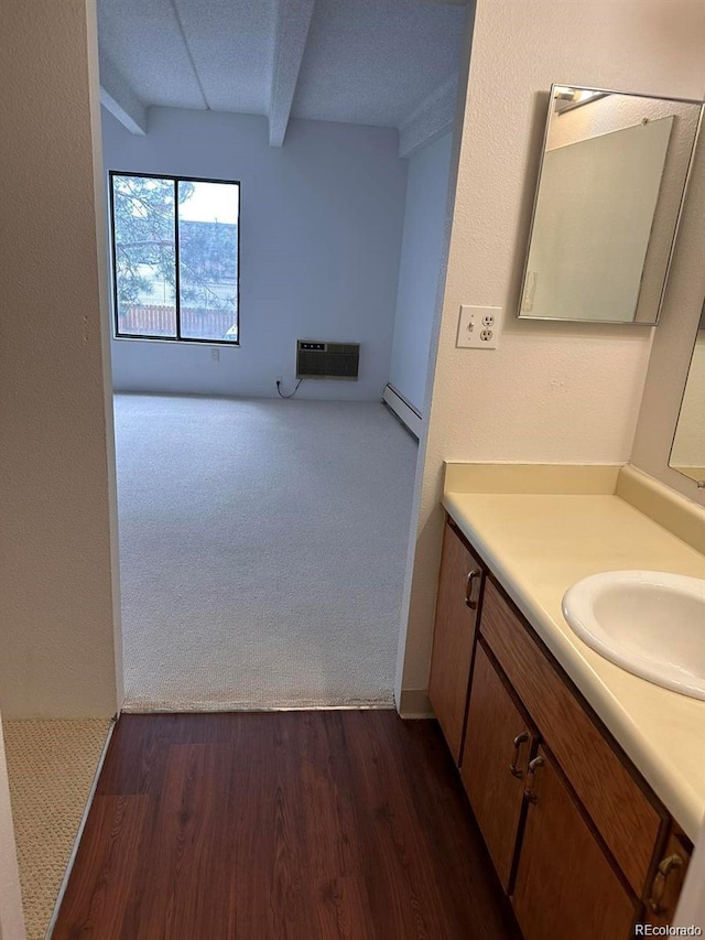 bathroom with an AC wall unit, vanity, beam ceiling, and wood finished floors