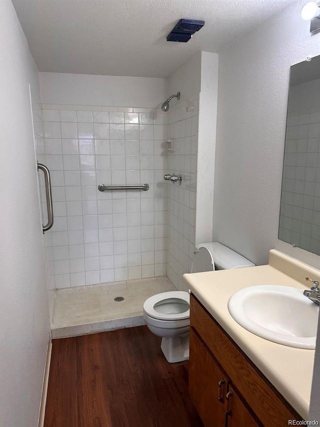 full bath featuring toilet, a stall shower, a textured ceiling, vanity, and wood finished floors