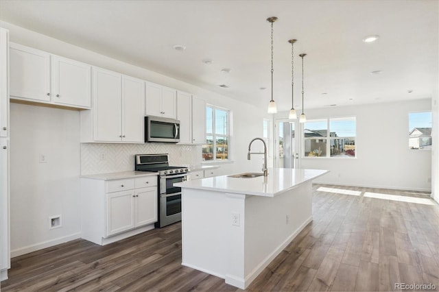 kitchen featuring white cabinetry, sink, stainless steel appliances, dark hardwood / wood-style flooring, and a center island with sink