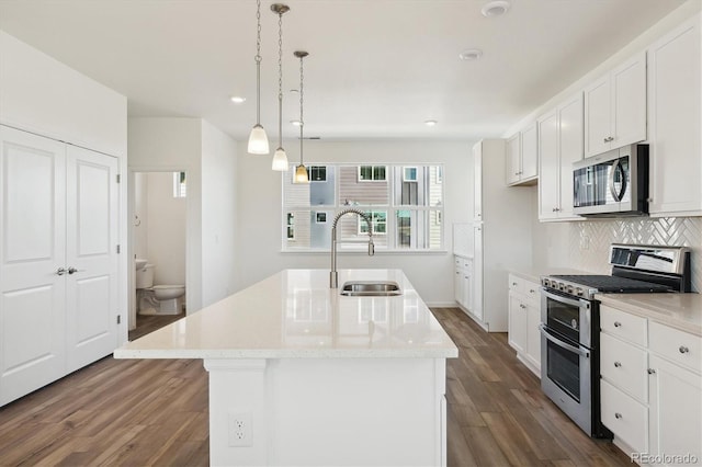 kitchen featuring a center island with sink, white cabinets, sink, dark hardwood / wood-style floors, and stainless steel appliances