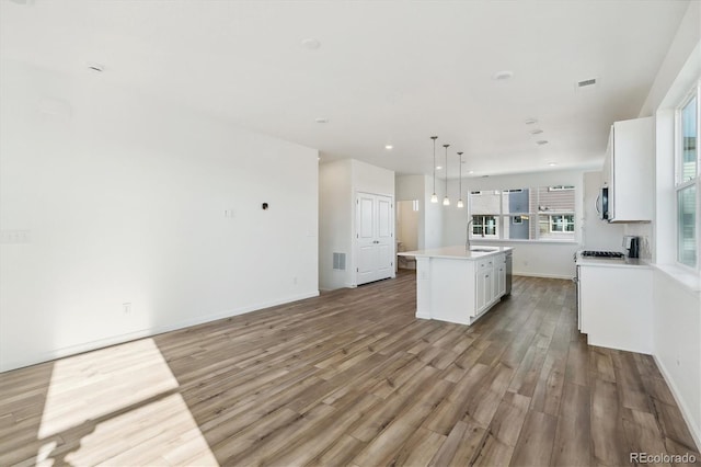 kitchen featuring white cabinetry, hanging light fixtures, light hardwood / wood-style flooring, white range with gas cooktop, and a kitchen island