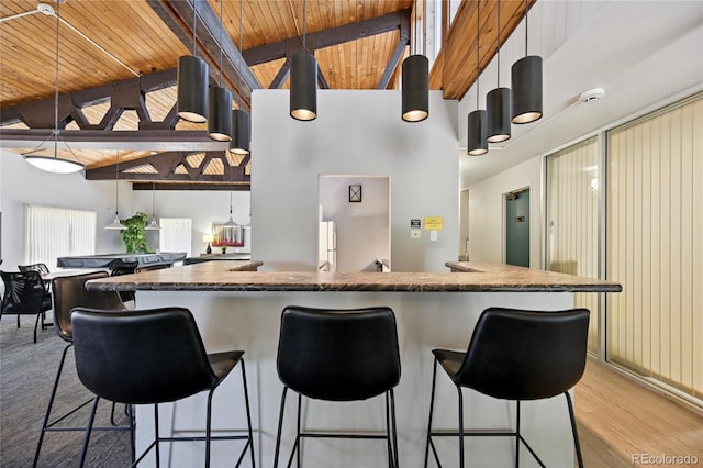 7020 E Girard Ave Unit 109, Denver, CO 80224 - kitchen featuring a wooden ceiling with exposed beams, dark countertops, high vaulted ceiling, light wood-style flooring, and a breakfast bar area
