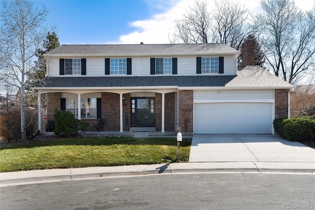 traditional-style house featuring brick siding, covered porch, driveway, and a front yard