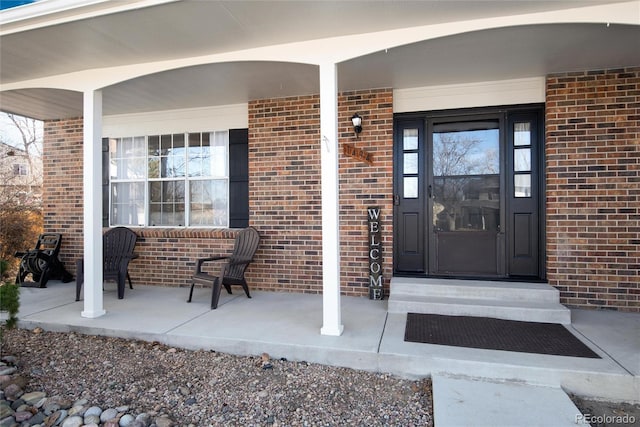 entrance to property featuring brick siding and covered porch