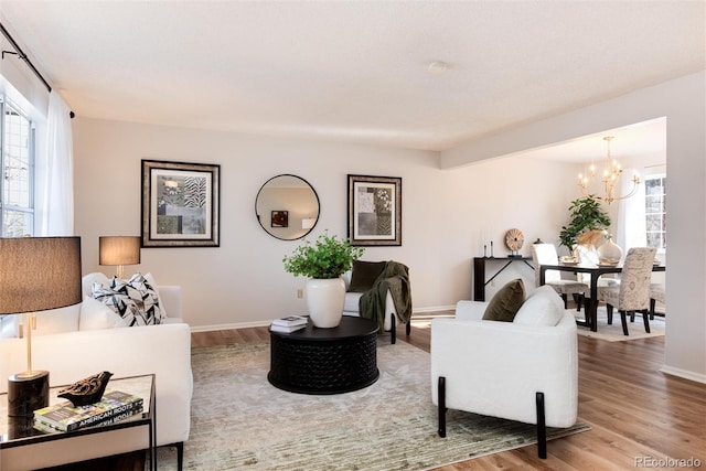 living room with a chandelier, baseboards, and wood finished floors