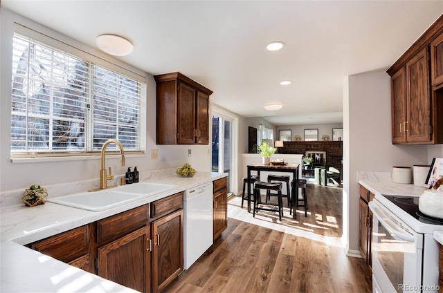 kitchen with a sink, white appliances, plenty of natural light, and wood finished floors