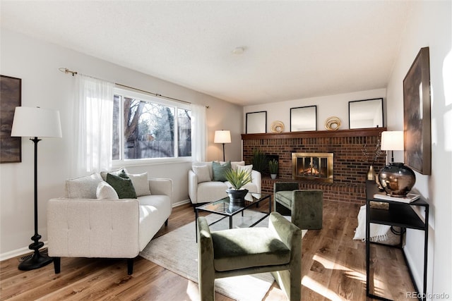 living area featuring a brick fireplace, wood finished floors, and baseboards