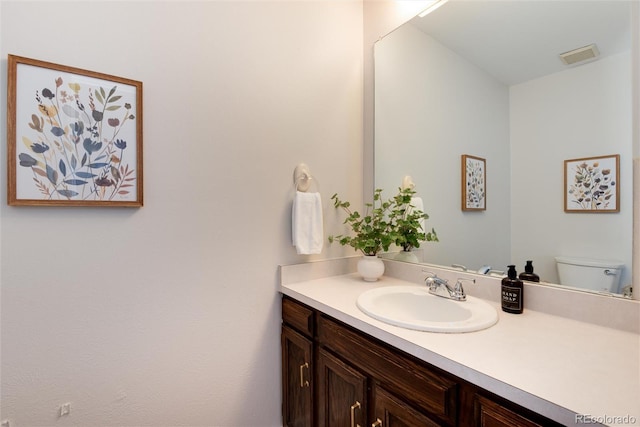 bathroom with visible vents, toilet, and vanity