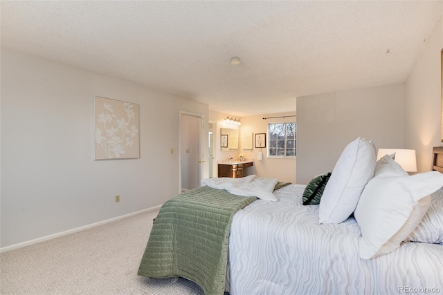 carpeted bedroom featuring baseboards, a textured ceiling, and ensuite bathroom