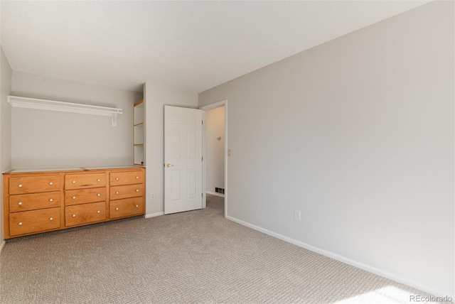 unfurnished bedroom with baseboards, light carpet, and visible vents