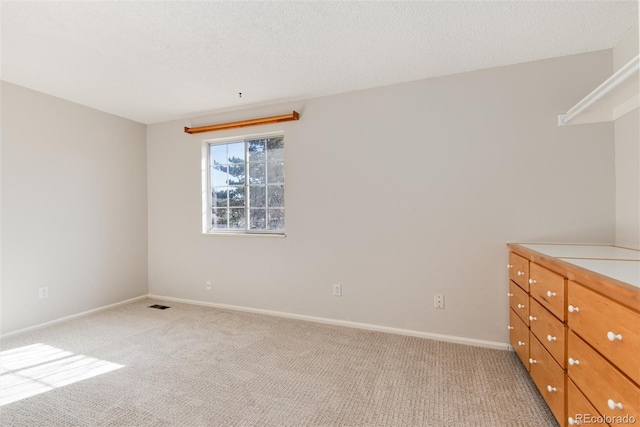 unfurnished bedroom with light carpet, visible vents, a textured ceiling, and baseboards