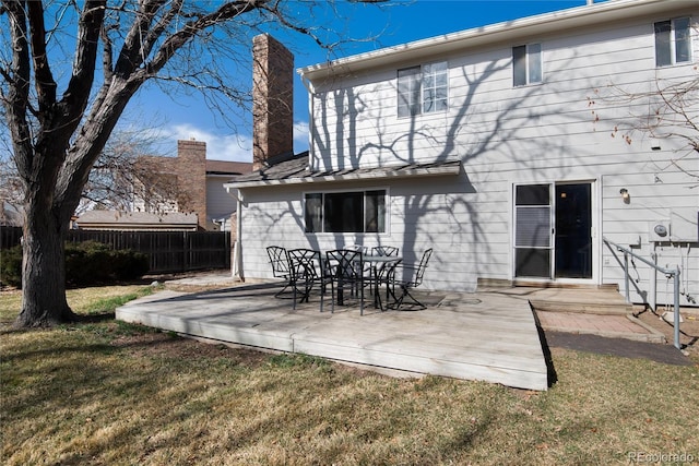 rear view of house with a lawn, a deck, and fence