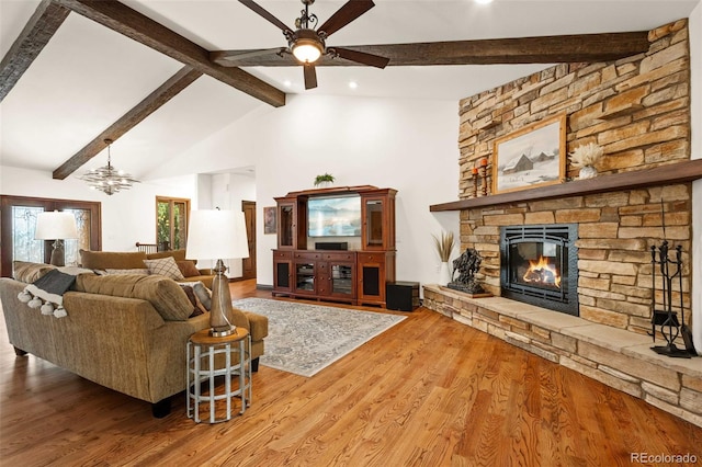 living room with vaulted ceiling with beams, a stone fireplace, ceiling fan, and hardwood / wood-style flooring