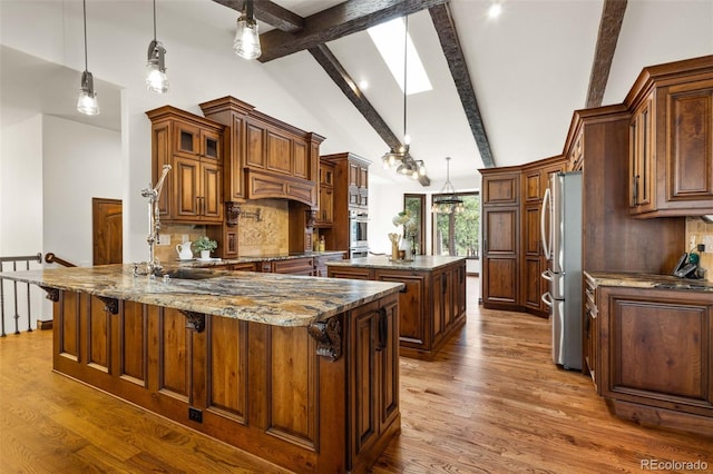 kitchen featuring appliances with stainless steel finishes, hardwood / wood-style floors, pendant lighting, a skylight, and beam ceiling